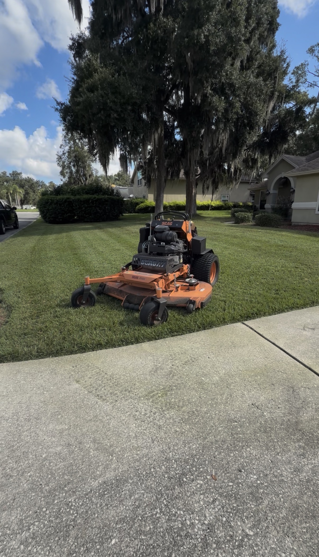 Scag mower on a freshly maintained lawn beneath oak trees