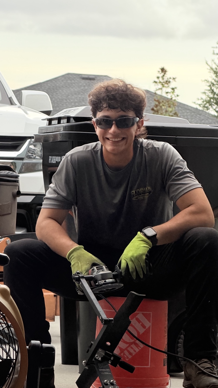 Sergio smiling in his work shirt and gloves while maintaining equipment